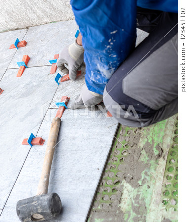 Tiler at work installing new floor with tiles. Construction. 123451102