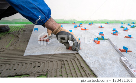 Tiler at work installing new floor with tiles. Construction. Tiler at work installing new floor with tiles. Construction. 123451105