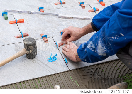 Tiler at work installing new floor with tiles. Construction. 123451107