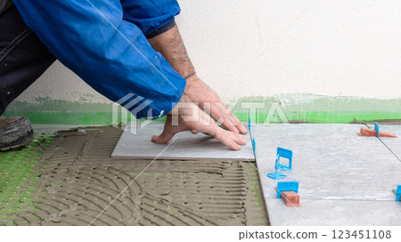 Tiler at work installing new floor with tiles. Construction. Tiler at work installing new floor with tiles. Construction. 123451108