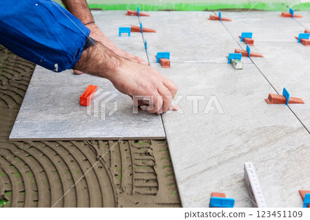 Tiler at work installing new floor with tiles. Construction. Tiler at work installing new floor with tiles. Construction. 123451109