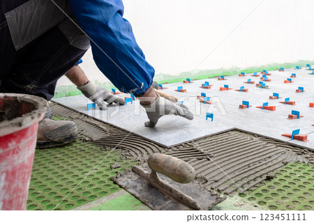 Tiler at work installing new floor with tiles. Construction. 123451111