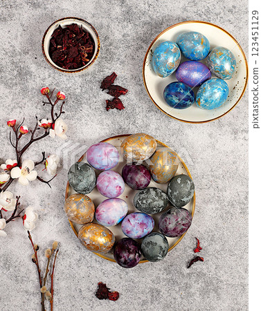 Easter celebration concept, Easter marble eggs dyed with natural hibiscus tea with sakura branch on concrete gray background. holiday card and ideas for preparing for the great holiday 123451129