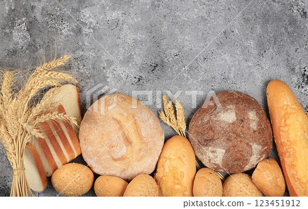 Assortment of homemade sourdough bread with crispy crust and ears of rye and wheat on gray concrete background with place for text, modern bakery concept, top view, healthy natural food, selective Assortment of homemade sourdough bread with crispy crust and ears of rye and wheat on gray concrete background with place for text, modern bakery concept, top view, healthy natural food, selective 123451912
