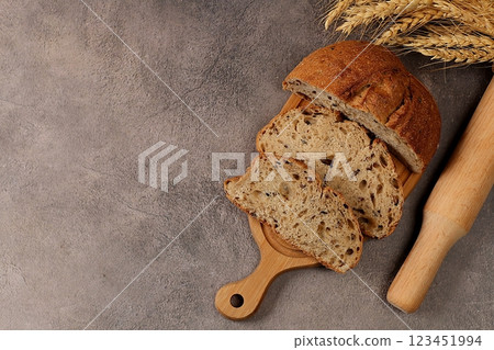 Freshly baked homemade bread, whole grain sourdough bread with a crispy crust, sliced and ears of rye and wheat on a concrete background with space for text, modern baking concept, healthy natural Freshly baked homemade bread, whole grain sourdough bread with a crispy crust, sliced and ears of rye and wheat on a concrete background with space for text, modern baking concept, healthy natural 123451994
