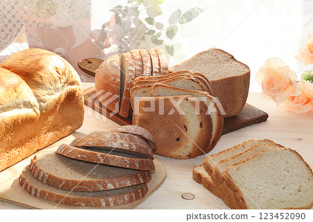 Loaf and slices of fresh white and black bread on a sunny rustic table, diet food, selective focus. Healthy food and natural ecological product. Loaf and slices of fresh white and black bread on a sunny rustic table, diet food, selective focus. Healthy food and natural ecological product. 123452090