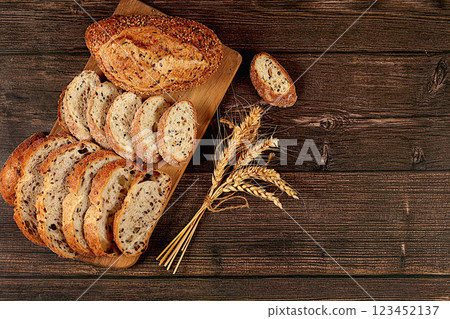 Freshly baked whole grain homemade sourdough bread with crispy crust, sliced and ears of wheat on wooden table, modern baking concept, healthy natural food Freshly baked whole grain homemade sourdough bread with crispy crust, sliced and ears of wheat on wooden table, modern baking concept, healthy natural food 123452137