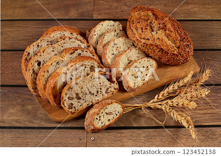 Freshly baked whole grain homemade sourdough bread with crispy crust, sliced and ears of wheat on wooden table, modern baking concept, healthy natural food Freshly baked whole grain homemade sourdough bread with crispy crust, sliced and ears of wheat on wooden table, modern baking concept, healthy natural food 123452138