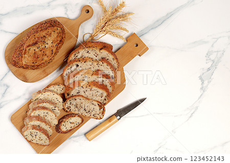 Freshly baked whole grain homemade sourdough bread with crispy crust, sliced and ears of wheat on marble background, modern baking concept, healthy natural food 123452143