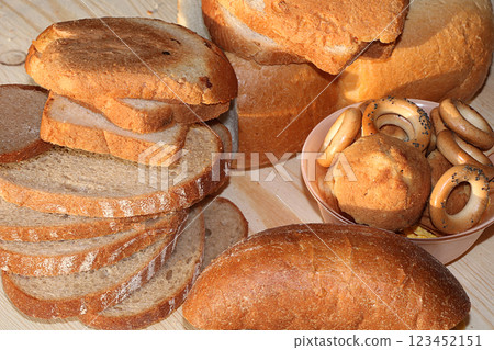 Loaf and slices of fresh white and black bread on a sunny rustic table, diet food, selective focus. Healthy food and natural ecological product. Loaf and slices of fresh white and black bread on a sunny rustic table, diet food, selective focus. Healthy food and natural ecological product. 123452151