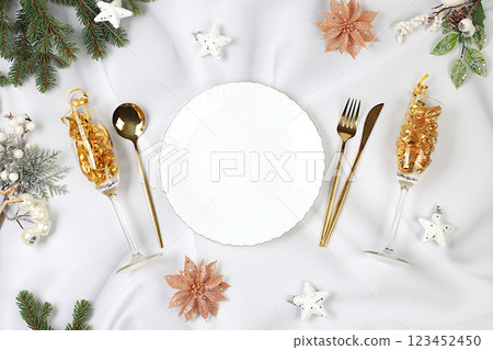Christmas table setting. Festive New Year's cutlery with a napkin on a plate on a marble concrete background, festive composition with fir branches and a glass of champagne, kitchen background. Christmas table setting. Festive New Year's cutlery with a napkin on a plate on a marble concrete background, festive composition with fir branches and a glass of champagne, kitchen background. 123452450