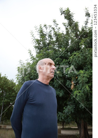 Bald Senior Man In Nature Park Looks In Shock Near Trees Outdoor Bald Senior Man In Nature Park Looks In Shock Near Trees Outdoor 123453334