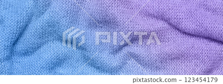 A soft and textured gradient blue and purple knitted fabric with gentle waves and folds, creating a cozy and warm appearance. Ideal for textile backgrounds, fashion, or home decor themes. A soft and textured gradient blue and purple knitted fabric with gentle waves and folds, creating a cozy and warm appearance. Ideal for textile backgrounds, fashion, or home decor themes. 123454179