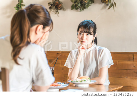 Young Asian woman having lunch at a cafe and making friends for trouble consultation Young Asian woman having lunch at a cafe and making friends for trouble consultation 123455253
