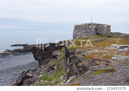 Old abandoned stone pillbox on a rocky seashore 123455570