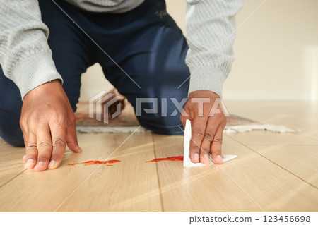 Cleaning up a spilled sauce on hardwood floor in a bright room Cleaning up a spilled sauce on hardwood floor in a bright room 123456698
