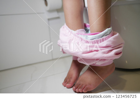 Child in pink pants using the toilet in a modern bathroom setting Child in pink pants using the toilet in a modern bathroom setting 123456725