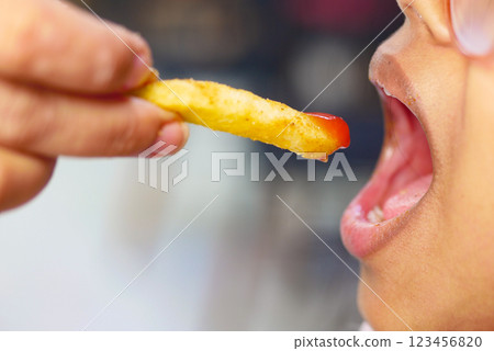Child enjoys a delicious french fry dipped in ketchup at lunch Child enjoys a delicious french fry dipped in ketchup at lunch 123456820