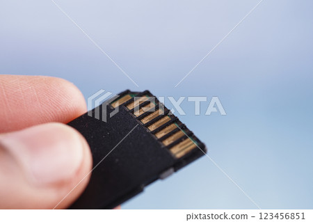 Hand holding a micro SD card with a blurred background Hand holding a micro SD card with a blurred background 123456851