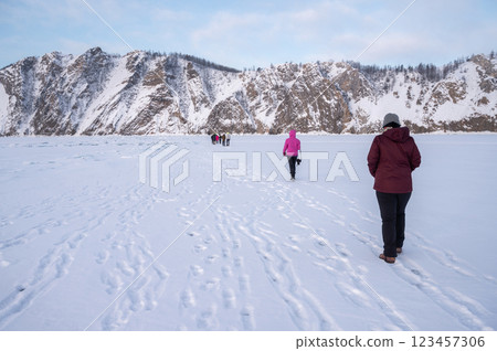 Tourist walking on the frozen lake Baikal nearly Uzury bay the Eastern shore of Olkhon Island, Russia. Tourist walking on the frozen lake Baikal nearly Uzury bay the Eastern shore of Olkhon Island, Russia. 123457306