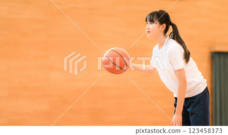 Junior high school and high school girls in gym clothes playing basketball in a gymnasium Junior high school and high school girls in gym clothes playing basketball in a gymnasium 123458373