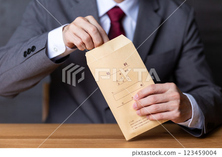 一位身穿灰色西裝、手持薪水信封的中年男性商人 一位身穿灰色西裝、手持薪水信封的中年男性商人 123459004