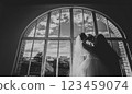 Bride and groom kissing against a semicircular window 123459074