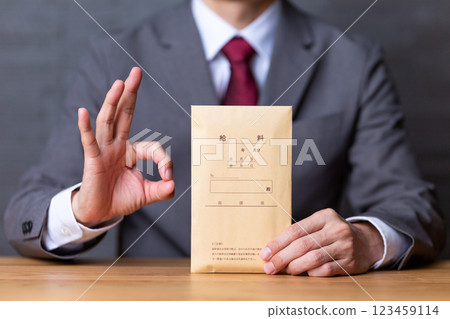 一位中年男性商人身穿灰色西裝，手拿薪水信封，畫著一個圓圈標誌 123459114