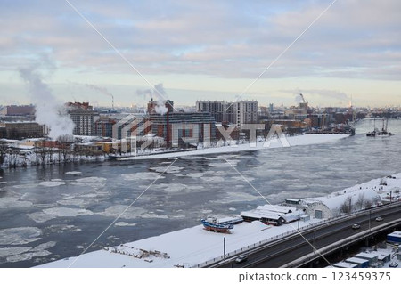 A scenic winter view of an industrial waterfront with a frozen river running through 123459375