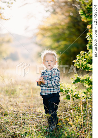 Little girl stands half-turned with her mouth open in a clearing Little girl stands half-turned with her mouth open in a clearing 123459574