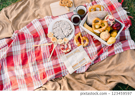Sliced pie on a plate stands on a bedspread next to a basket of food and mugs of coffee 123459597