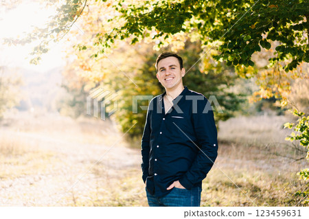 Smiling man standing on the sunny lawn near a tree 123459631