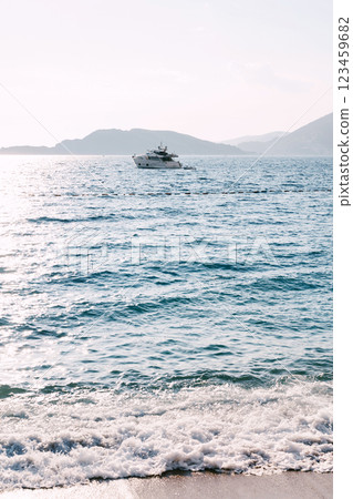 View from the shore to the yacht sailing on the sea against the backdrop of the mountains 123459682