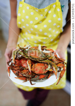 Housewife holds a plate of boiled crabs in her hands. Cropped. Faceless 123459731