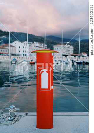 Red fire stand with a fire extinguisher inside stands on a yacht pier 123460152