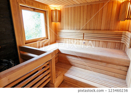 Wooden benches in the sauna with lamps in the corners near the window opposite the stove 123460236