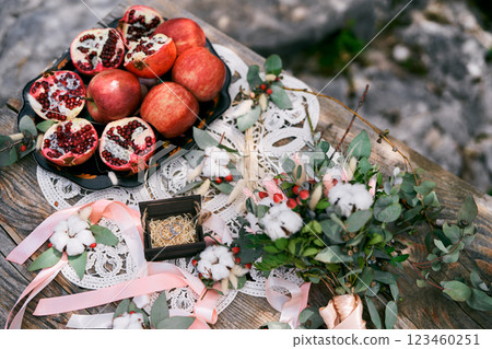 Box with wedding rings stands on a macrame napkin on the table next to fruit and a bouquet 123460251
