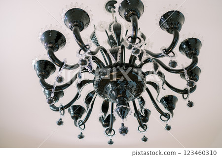 Black chandelier with white glass decor and pendants hangs on the ceiling 123460310