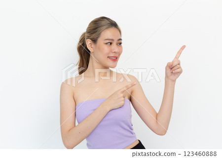 portrait of a Happy Asian woman smiling points her index finger at an empty space in the background and looks straight ahead on white background portrait of a Happy Asian woman smiling points her index finger at an empty space in the background and looks straight ahead on white background 123460888