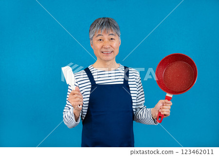 穿著圍裙，手拿煎鍋的中年男子 123462011