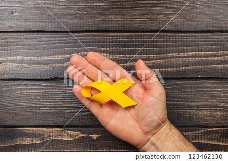 Holding a yellow ribbon to raise awareness for cancer and support survivors Holding a yellow ribbon to raise awareness for cancer and support survivors 123462130