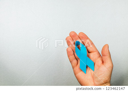 Hand holding a blue ribbon symbolizing awareness for cancer prevention 123462147