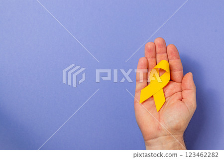 Holding a yellow ribbon to symbolize hope in cancer awareness campaign Holding a yellow ribbon to symbolize hope in cancer awareness campaign 123462282