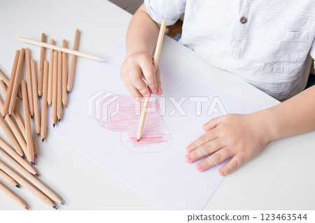 Young caucasian child drawing heart with colored pencils on paper Young caucasian child drawing heart with colored pencils on paper 123463544