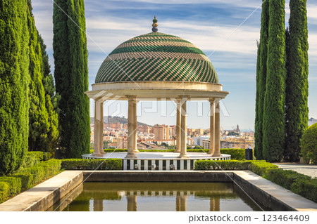 The Historical Botanical Garden La Concepcion in Malaga city at Andalusia, Spain, Europe. Elegant gazebo with a dome, overlooking a city from a manicured garden. 123464409