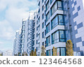 Side view of a multi-storey residential building of modern architecture with large windows against the background of the sky with clouds, the house is lined with white and gray slabs. The concept of 123464568