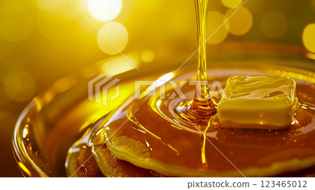 A close up of a bowl of honey being poured over a piece of butter A close up of a bowl of honey being poured over a piece of butter 123465012