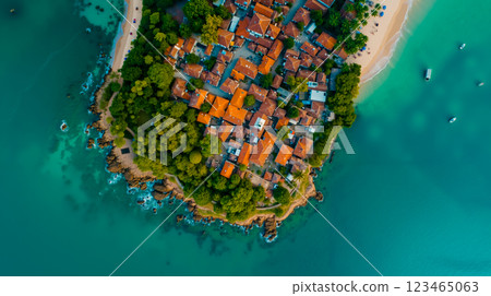 A small island in the middle of a body of water surrounded by trees 123465063