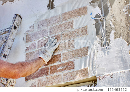 DIY faux brick wall, house painter glued panel with imitation bricks on facade. 123465332