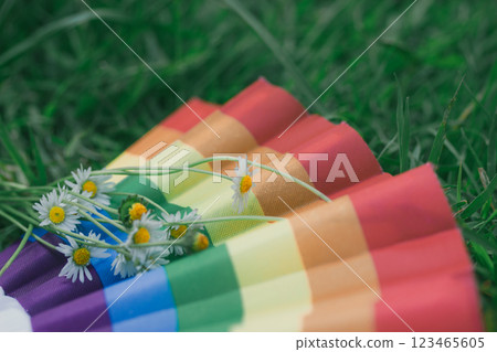 A rainbow fan with a bouquet of field white daisies lie in a green meadow in summer. Gay community concept. Pride Parade. Vintage pale colors backdrop A rainbow fan with a bouquet of field white daisies lie in a green meadow in summer. Gay community concept. Pride Parade. Vintage pale colors backdrop 123465605